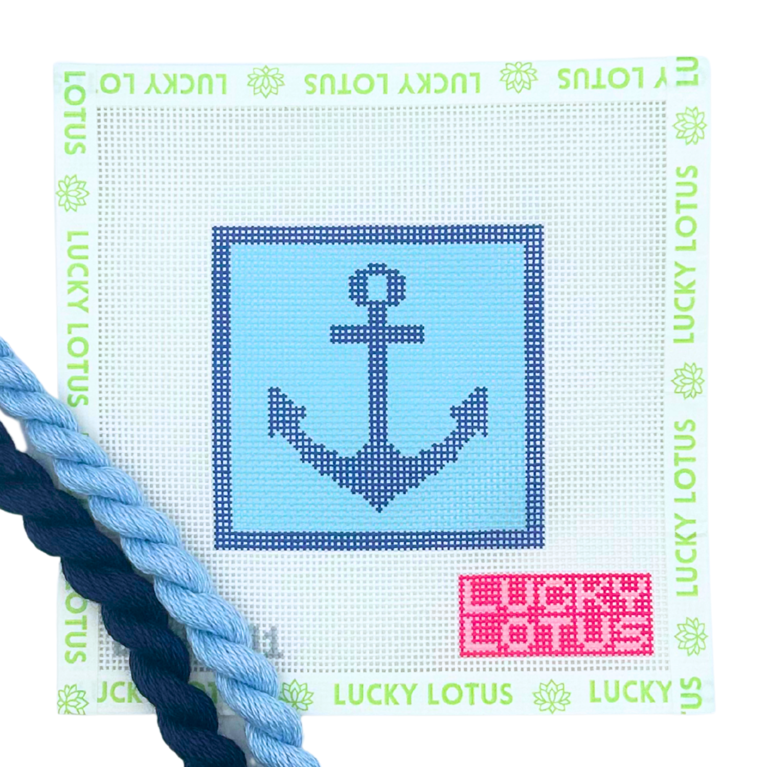 A needlepoint canvas featuring a navy blue anchor design on a light blue square, bordered by a white grid with green 'LUCKY LOTUS' text around the edge. A pink color code sticker is in the bottom right corner, and two braided needlepoint thread skeins (one light blue, one dark navy) are draped along the bottom left edge.