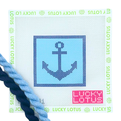 A needlepoint canvas featuring a navy blue anchor design on a light blue square, bordered by a white grid with green 'LUCKY LOTUS' text around the edge. A pink color code sticker is in the bottom right corner, and two braided needlepoint thread skeins (one light blue, one dark navy) are draped along the bottom left edge.