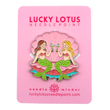 Mermaids needle minder featuring two mermaids sitting in a pink seashell while toasting with martinis, designed by Lucky Lotus Needlepoint.