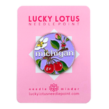 Michigan needle minder with red cherries, an apple blossom, green leaves, and Michigan lettering on a lavender background.