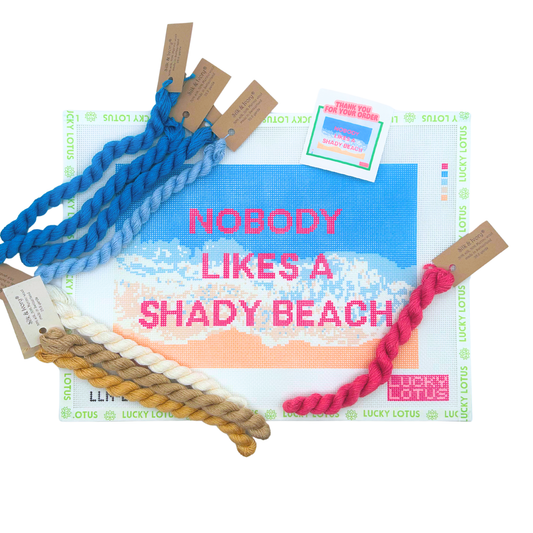 Nobody Likes a Shady Beach needlepoint canvas shown with coordinating Silk & Ivory threads in pink, cream, tan and blue.