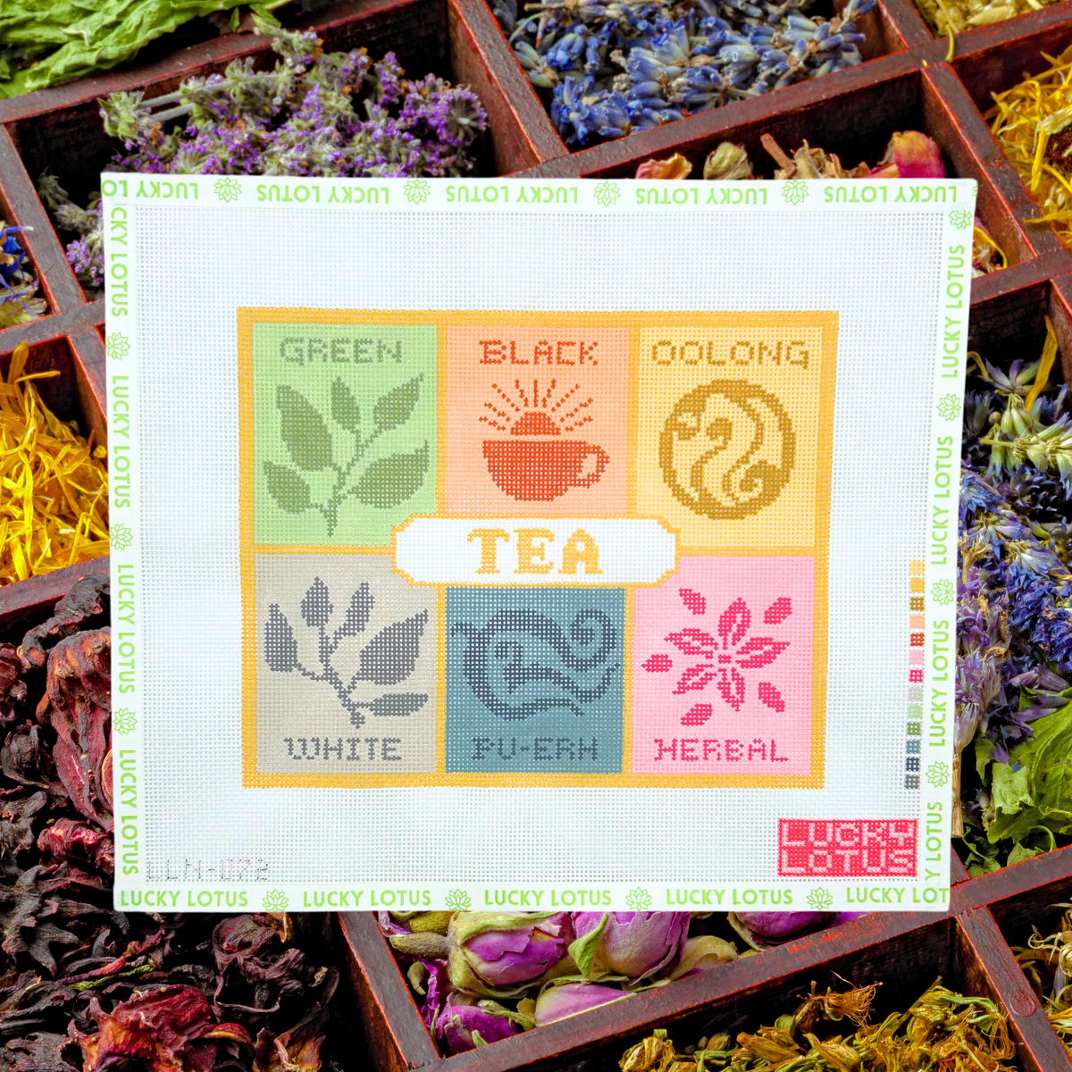 Lucky Lotus Needlepoint Tea Box canvas displayed over colorful loose leaf teas and dried botanicals.